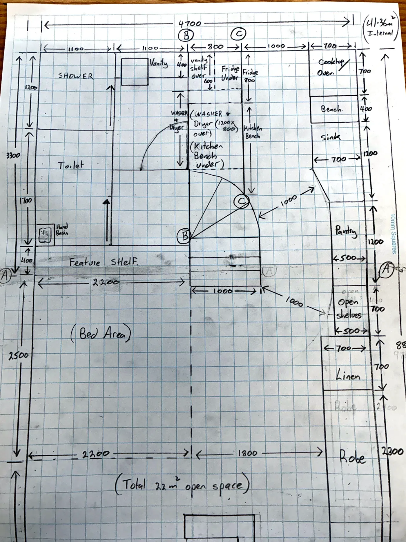 Hand-drawn floor plan of the new layout on graph paper, dimensioned: shower, toilet, vanity, washer and dryer, the curved stair, the galley kitchen, pantry, linen, robe and the bed area